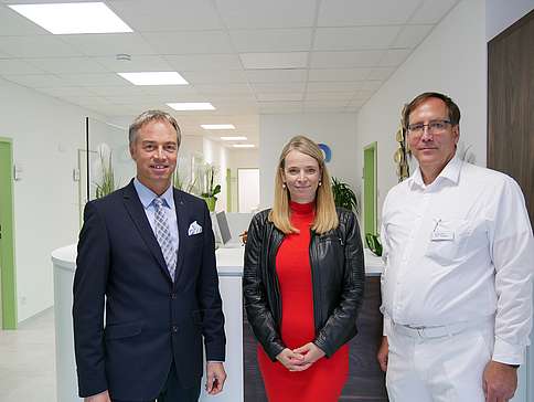 Michael Merz, Melitta Fechner und Sven Wacker stehen nebeneinander in der Arztpraxis und lächeln.